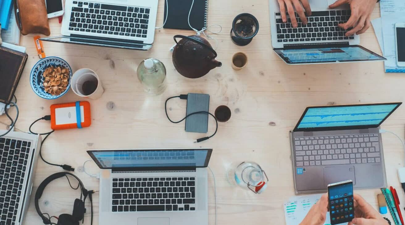 A Team Of Marketing Services Professionals Working On Laptops At A Table.